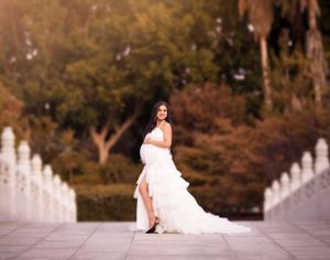 A bridal portrait on a white bridge with flowing dress and autumn trees in background.