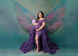 Ethereal maternity portrait with purple gown and painted butterfly wings against teal backdrop.