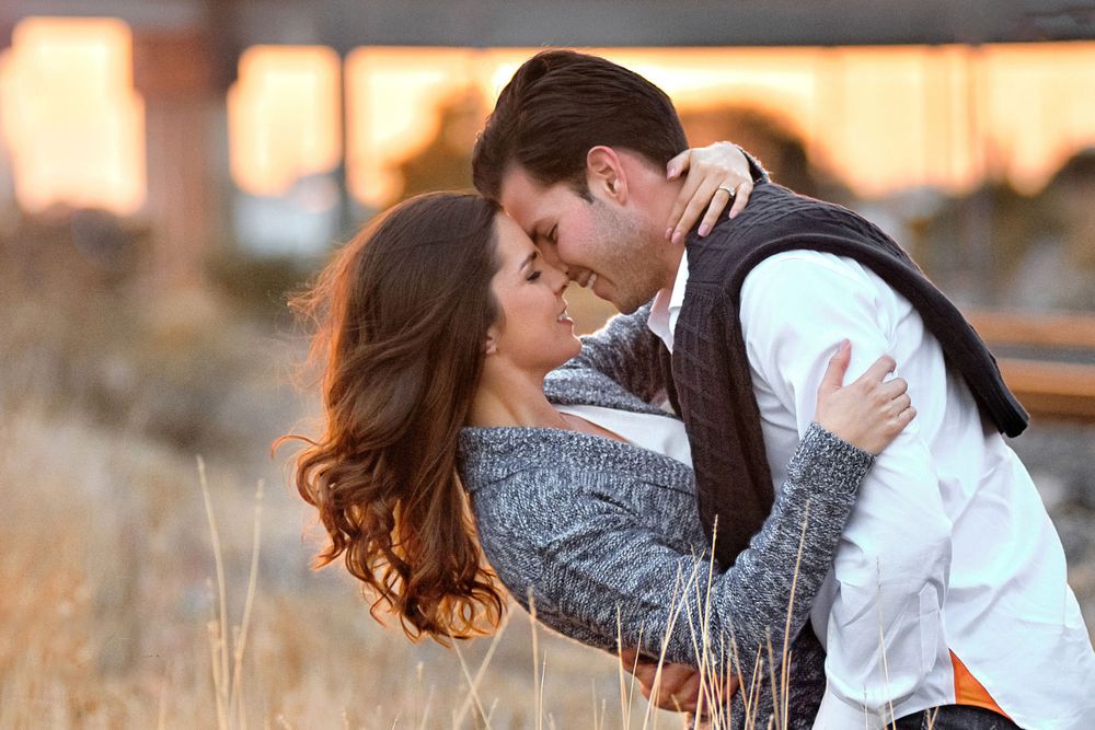 A romantic sunset embrace between a couple in a rustic field setting.