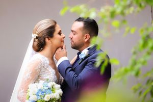 A tender moment between newlyweds with bride holding blue bouquet.