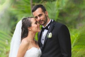 Intimate wedding portrait of couple surrounded by tropical greenery.