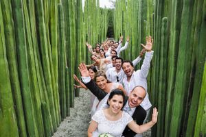 Wedding party poses playfully in bamboo forest pathway.