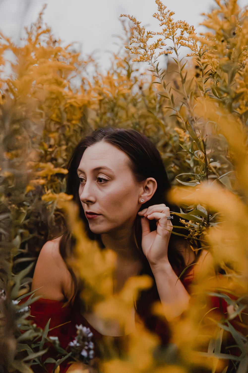 Portrait of someone in a red top surrounded by golden autumn foliage.