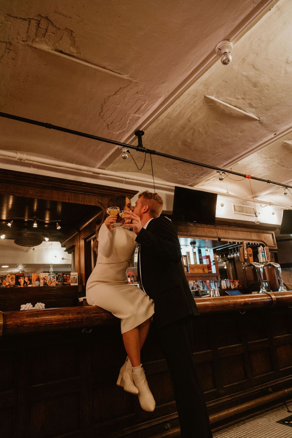 Long wooden bar counter in a basement venue with vintage decor and mood lighting.