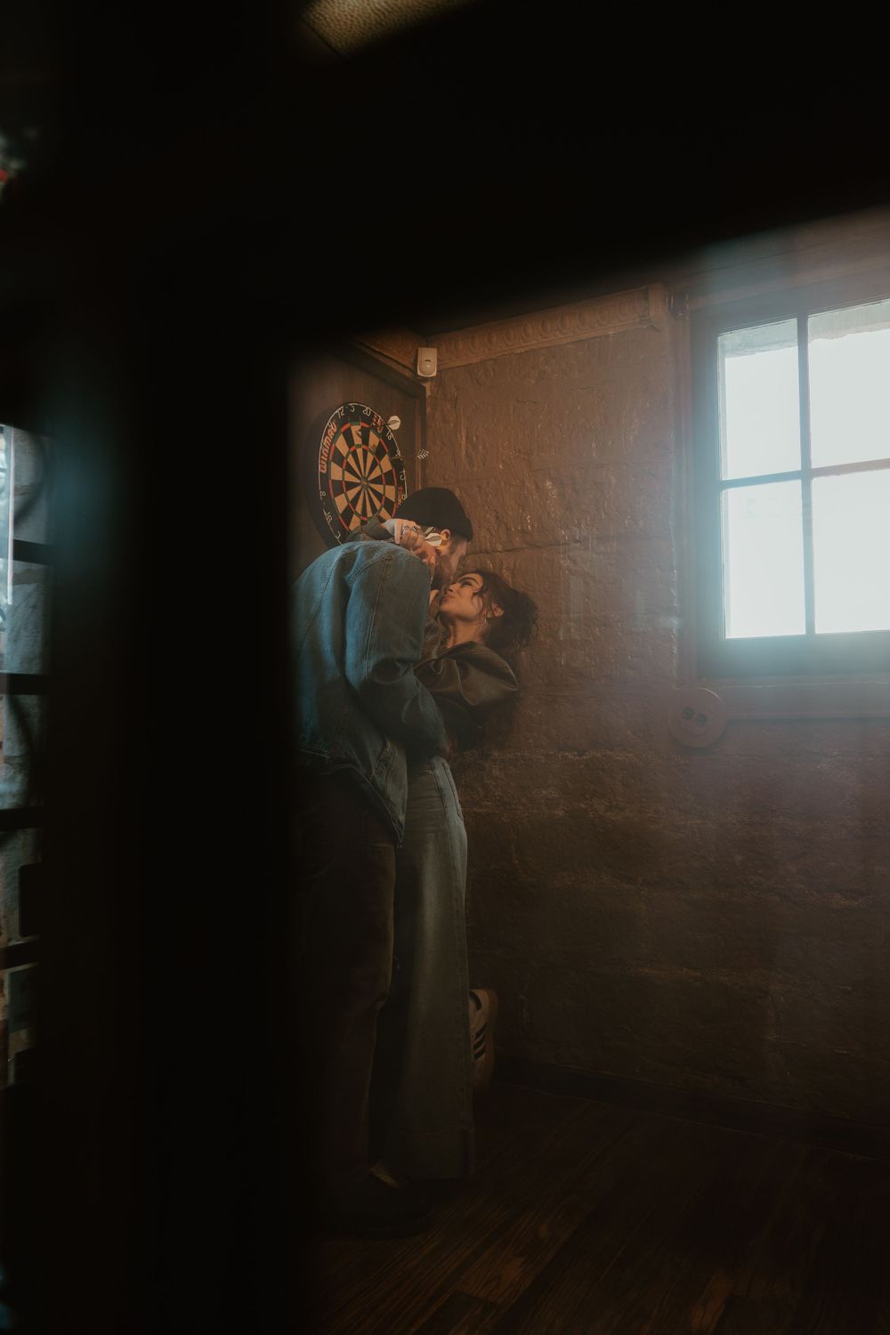Dark room with sunlight streaming through windows, creating dramatic shadows on brick walls.