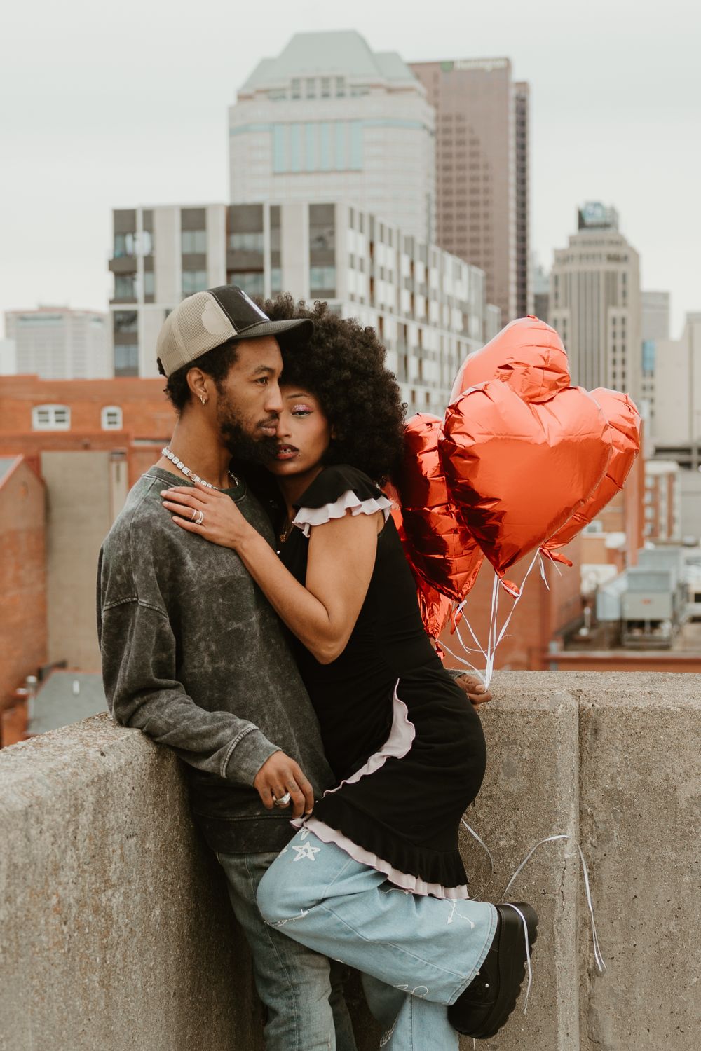 Romantic urban rooftop scene with heart balloons and city skyline in background.