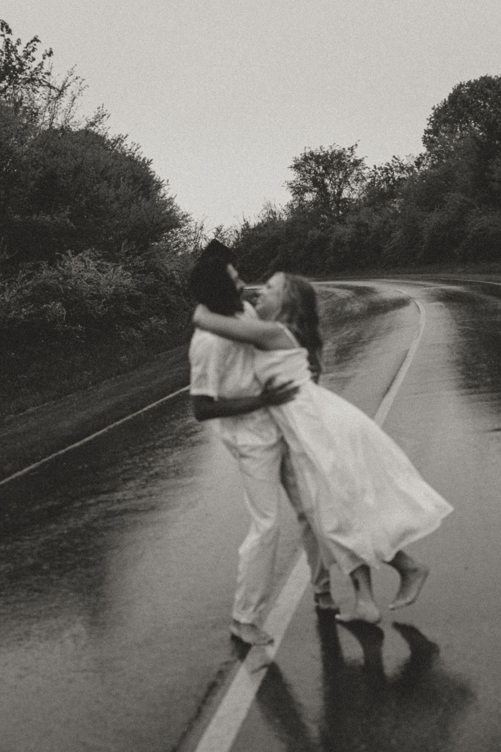 A black and white photo sequence showing a couple dancing and twirling together on a rainy road.
