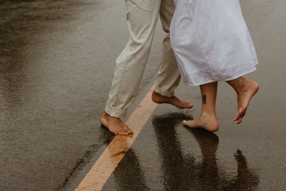 Couple's feet dancing together on a wooden floor in romantic wedding attire.
