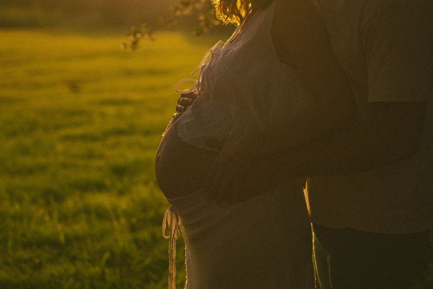 Maternity silhouette against a warm sunset backdrop in nature.