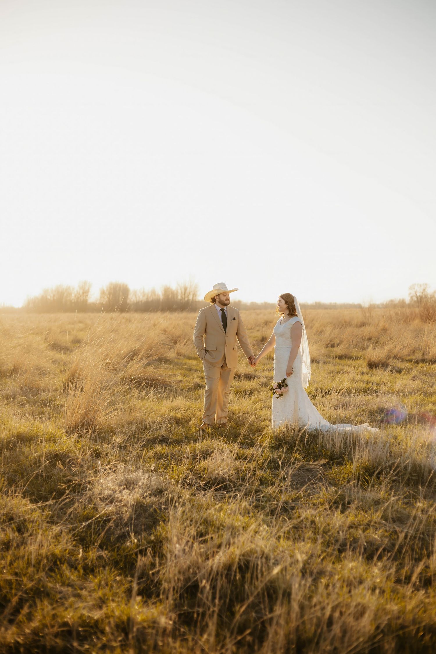 Romantic western sunset photograph of newlyweds in a golden field during golden hour.