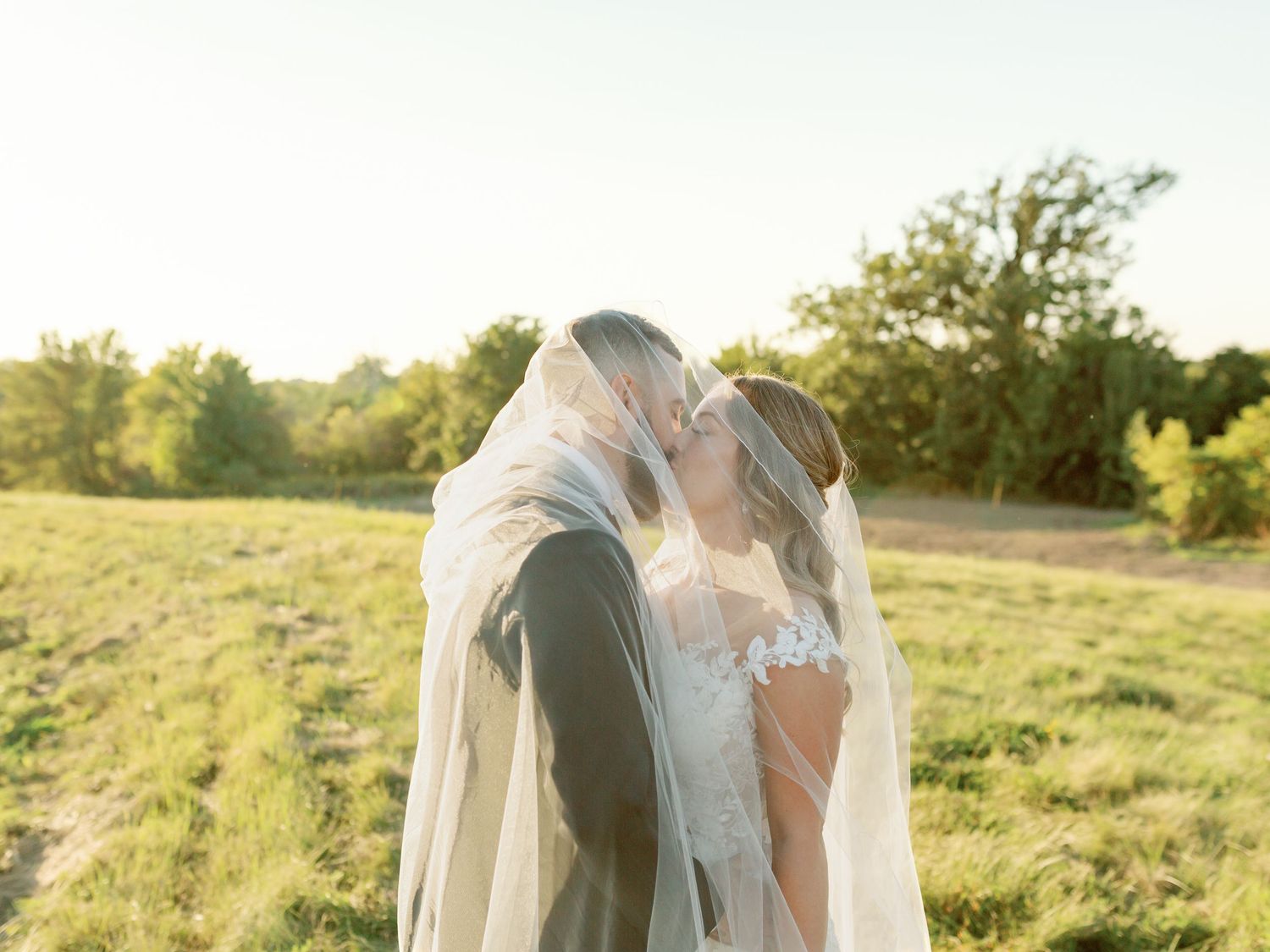 Piper's Heath Golf Club wedding captures a romantic moment as bride & groom embrace in a field at sunset by Katie Crane
