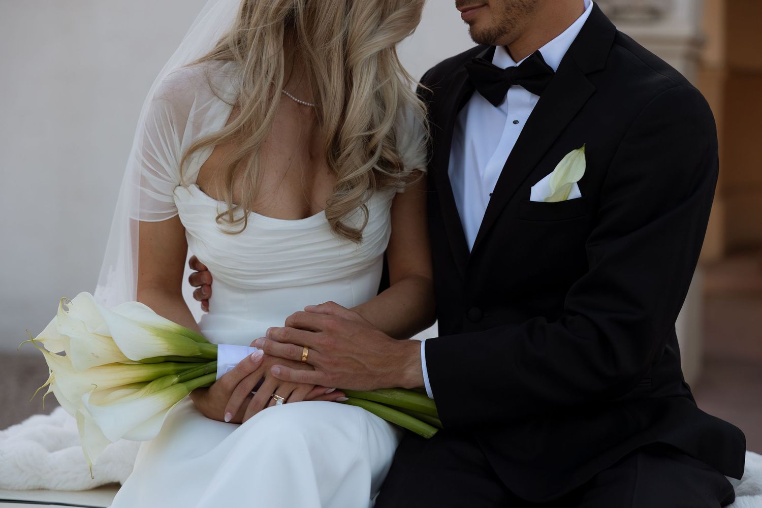 A close-up shot of a couple in wedding attire embracing outdoors at dusk, with a black suit and white dress.