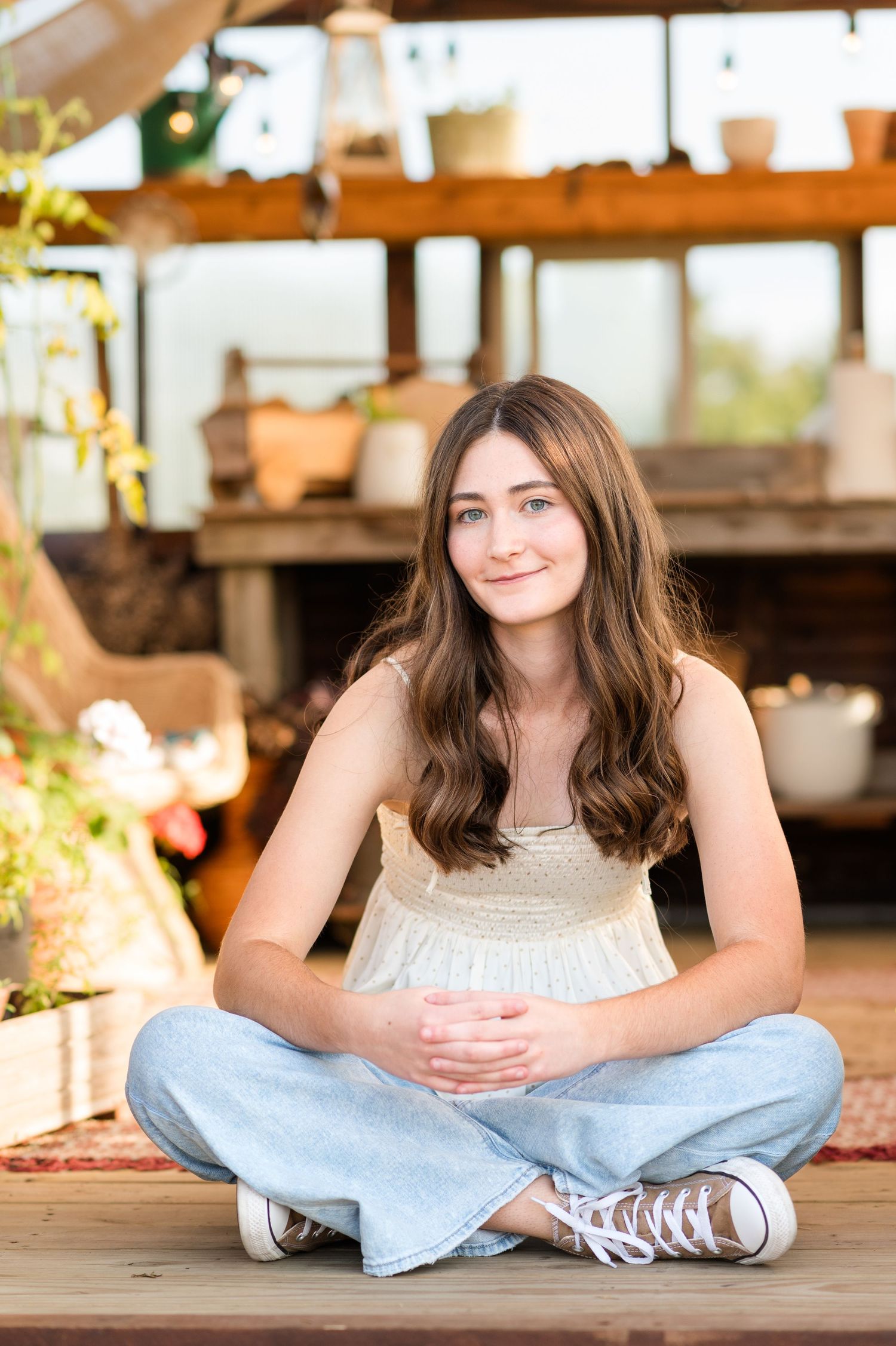 Heyworth, Illinois high school senior sitting among plants and flowers in a greenhouse during her senior session by Julie Loy Photography