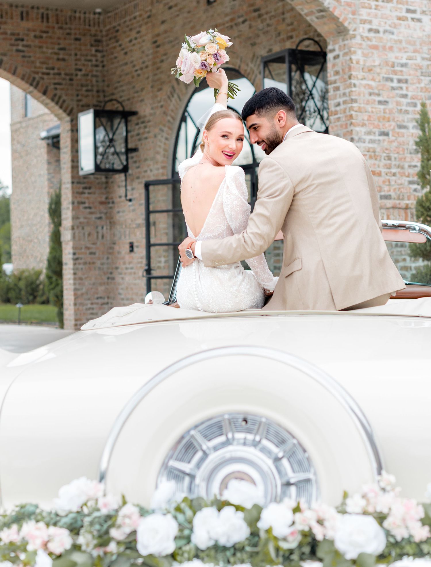 Bride and groom celebrating in a vintage car outside a Central Illinois wedding venue during their wedding day.
