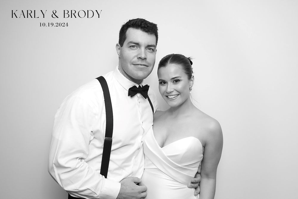 A black and white wedding portrait showing a couple in formal attire with suspenders and a strapless gown.