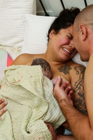 Tender moment shared on white bedding with green striped fabric visible.
