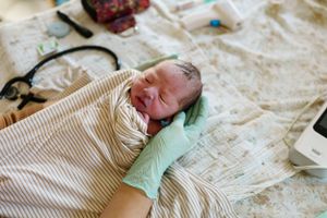 Baby resting on patterned bedding in soft natural light.