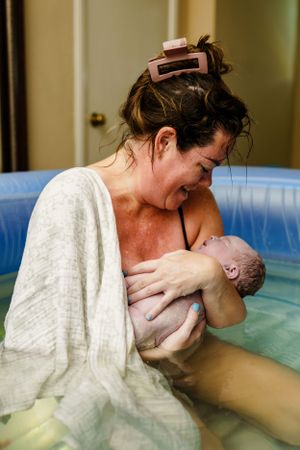 A tender water birth moment showing skin-to-skin bonding in a birthing pool.