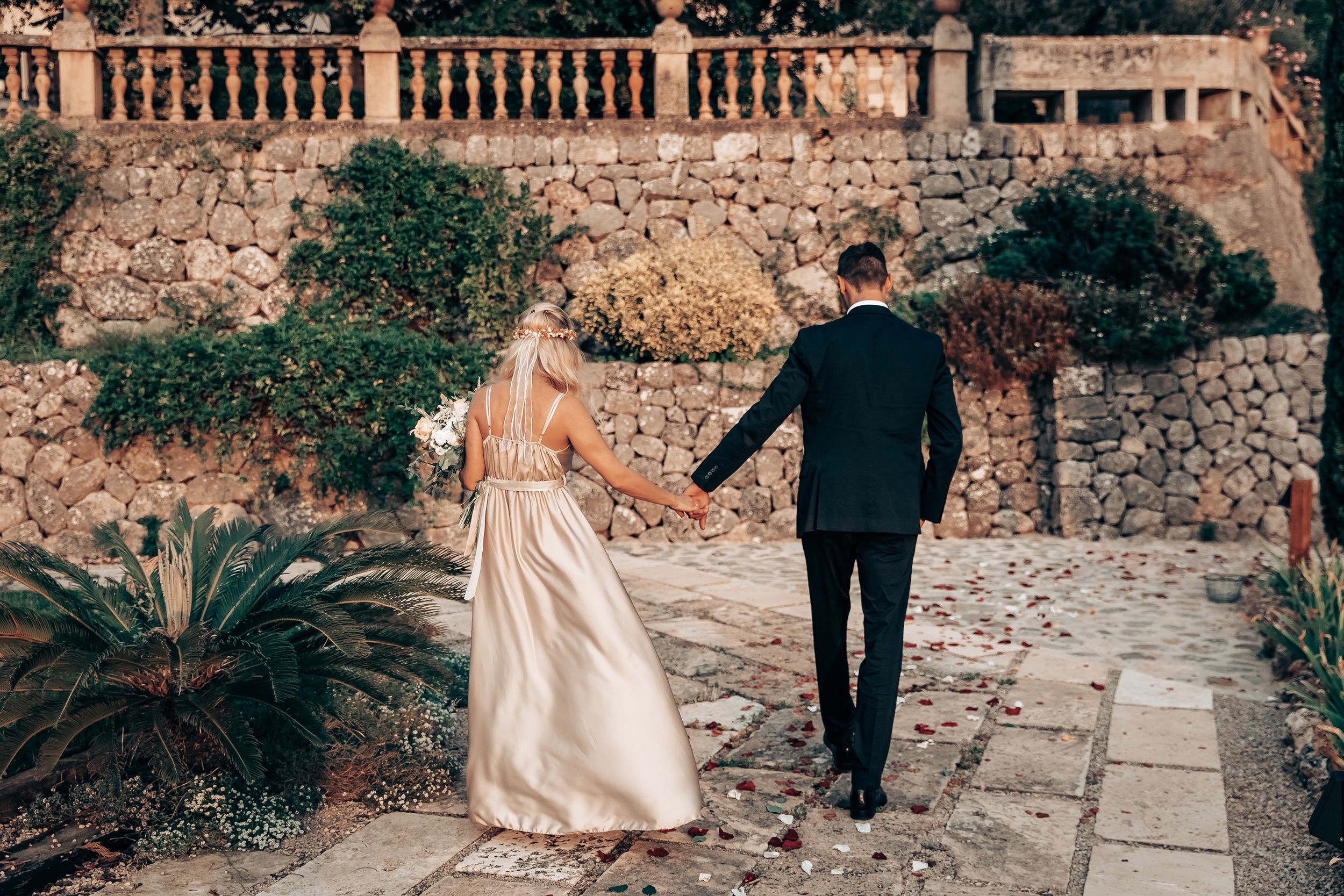 Romantic couple walking hand in hand through a meditteranean garden during an engagement photoshoot in Mallorca.