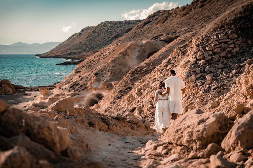 Bridal couple walking along a dramatic coastal cliff path overlooking the Mediterranean sea in Mallorca.