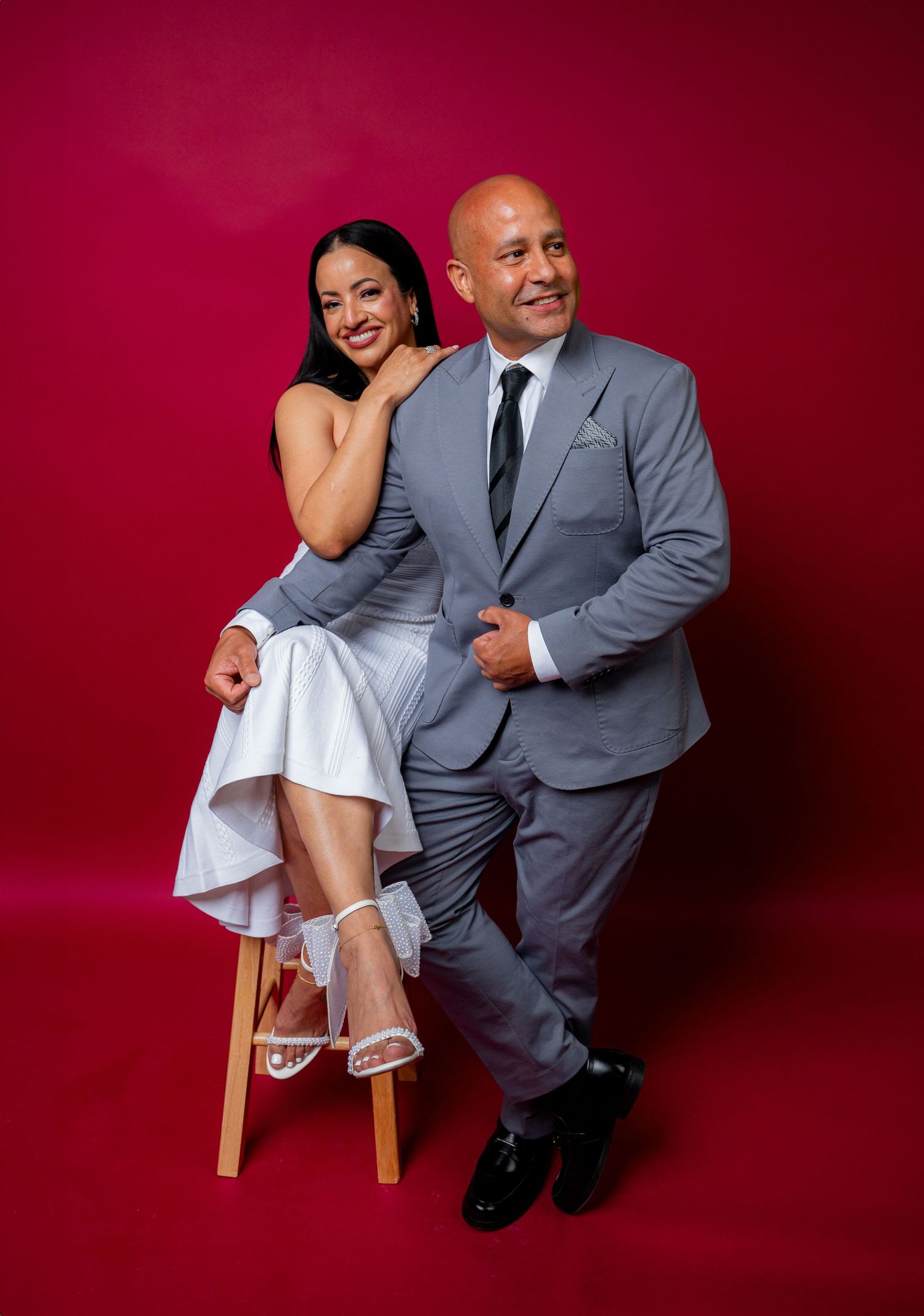 Studio portrait session showing playful poses against deep red background.