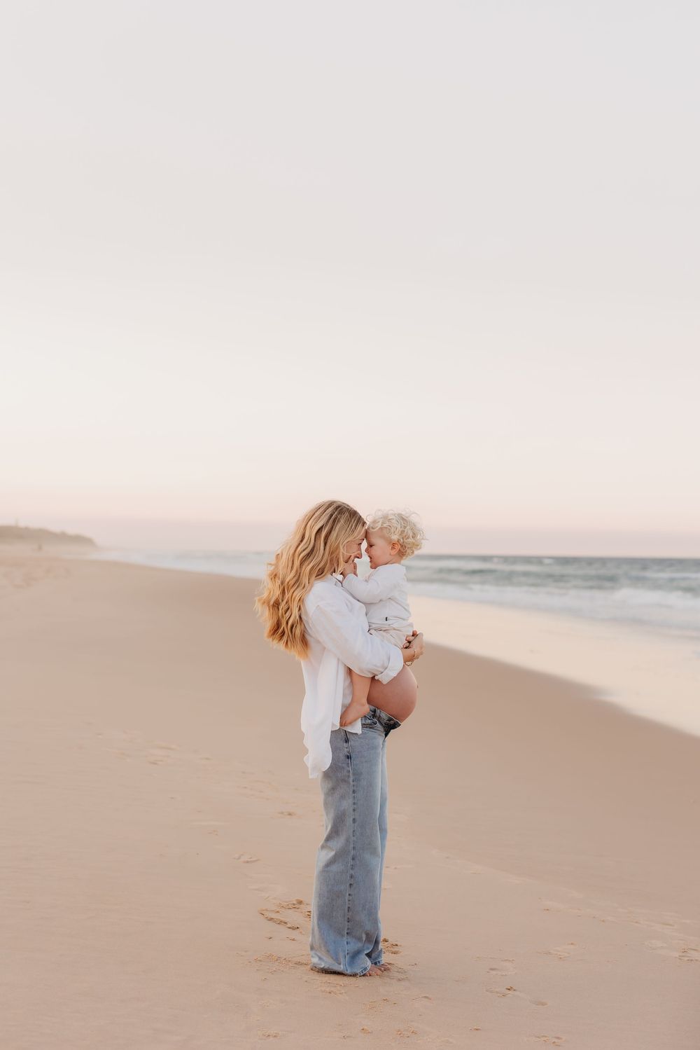 Mother holding toddler on the beach at sunset, Sunshine Coast maternity photography.