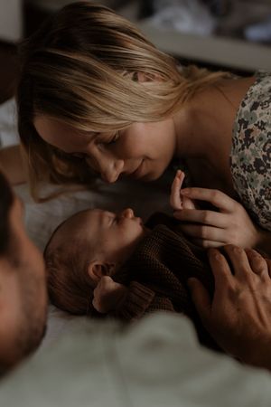 A tender moment between parent and infant as they lie close together in soft natural lighting.