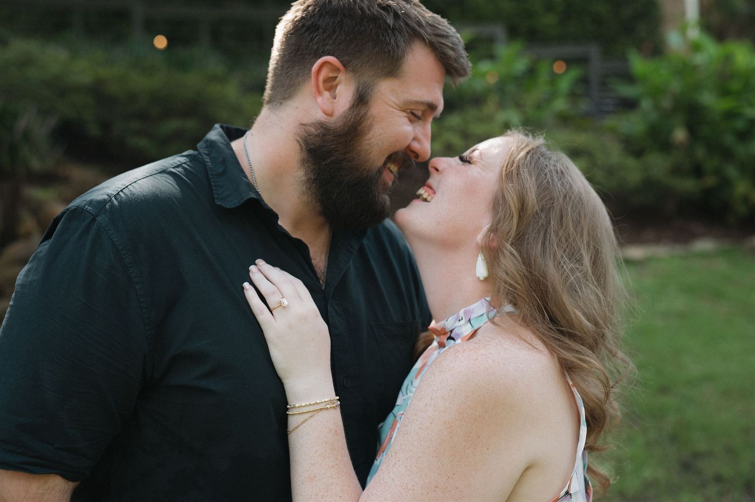 A romantic couple embraces outdoors in a garden setting during a tender moment at dusk.