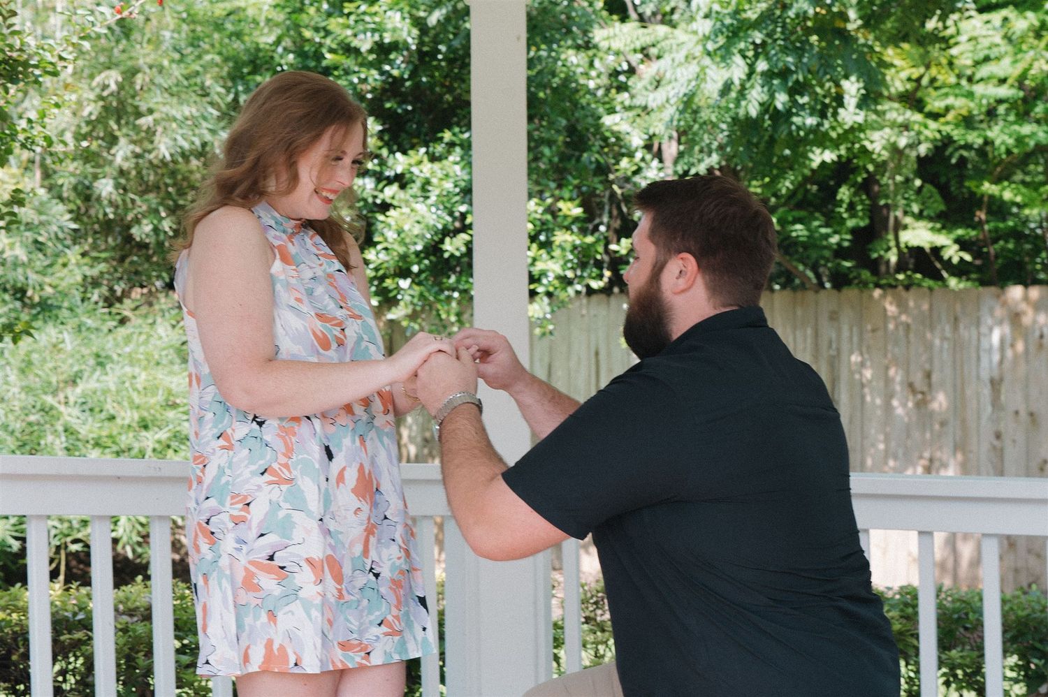 A romantic proposal moment takes place on a white porch surrounded by lush greenery.