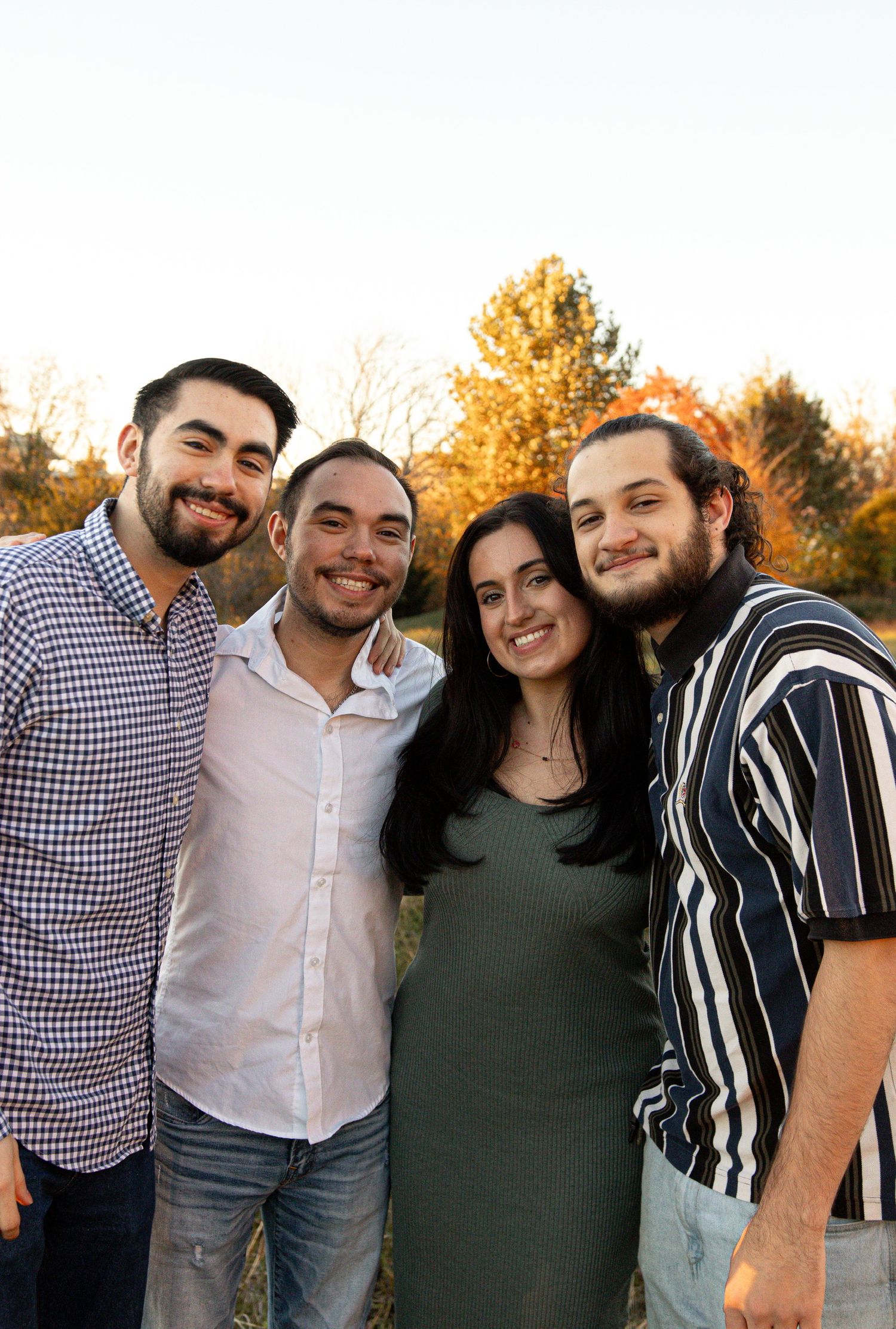 Four friends pose together outdoors during autumn sunset.