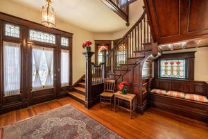 Grand foyer with wooden staircase, ornate trim work, and built-in bench seating.