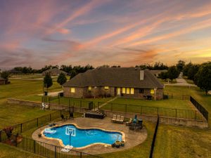Beautiful backyard with freeform swimming pool and patio furniture under a dramatic sunset sky.
