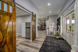 Modern farmhouse entryway with rustic barn door, hardwood floors, and contemporary lighting in an open hallway design.