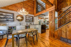 Modern rustic open concept kitchen and dining area with wood beams and antler chandelier.