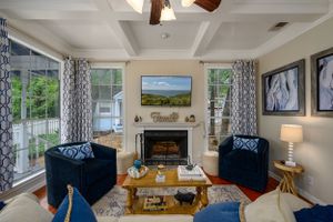 Elegant living room featuring coffered ceiling, fireplace, and navy blue accent chairs.