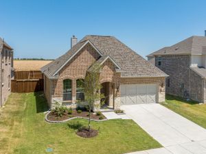Modern brick house with stone accents and manicured front yard featuring a two-car garage and curved driveway.