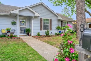 Charming gray ranch home with pink flowers and landscaped front entrance.