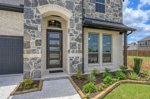 Modern stone and siding home exterior with decorative trim and window features against blue sky.
