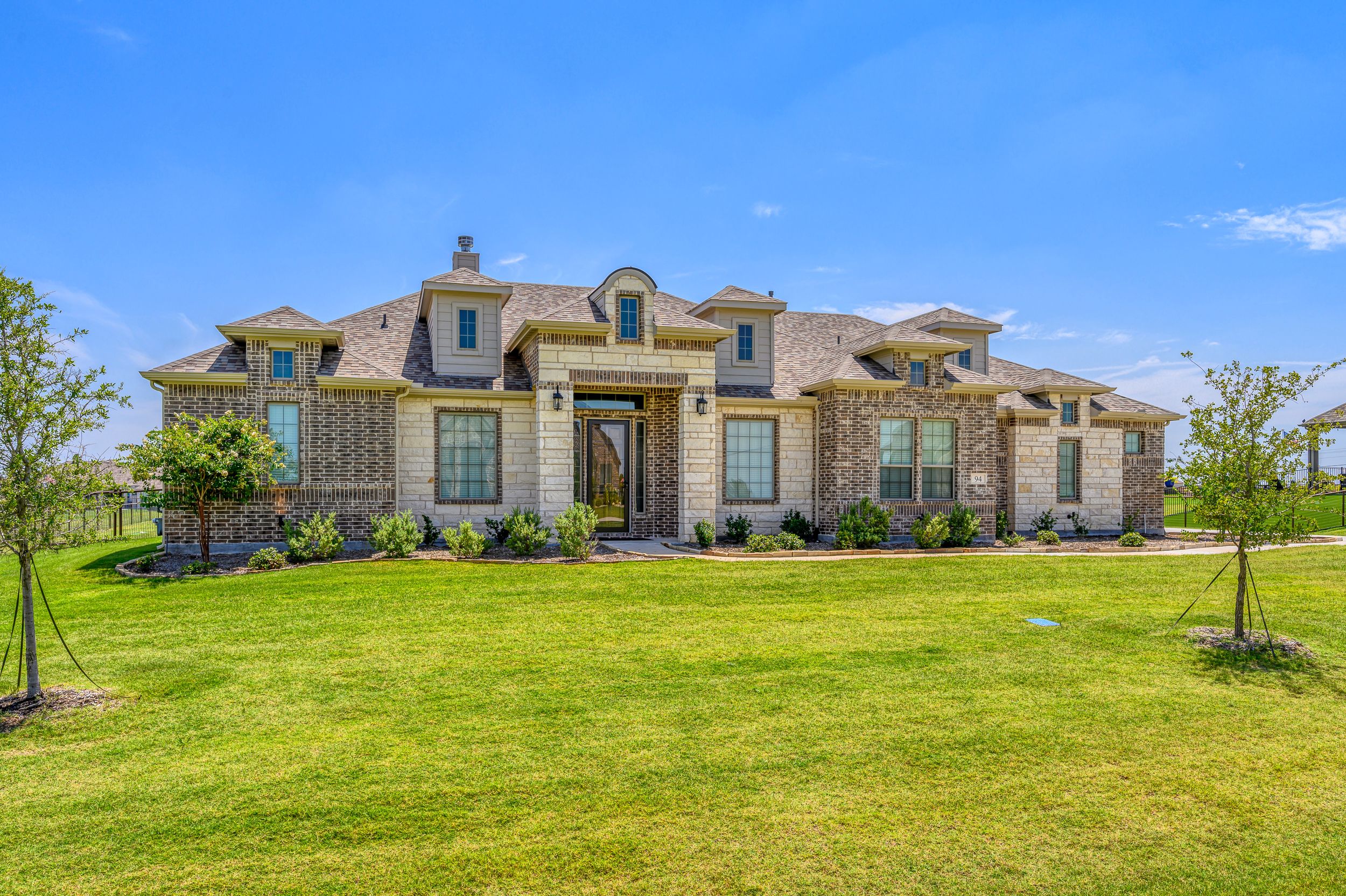 Panoramic view of luxury homes on a grassy hillside under blue sky.