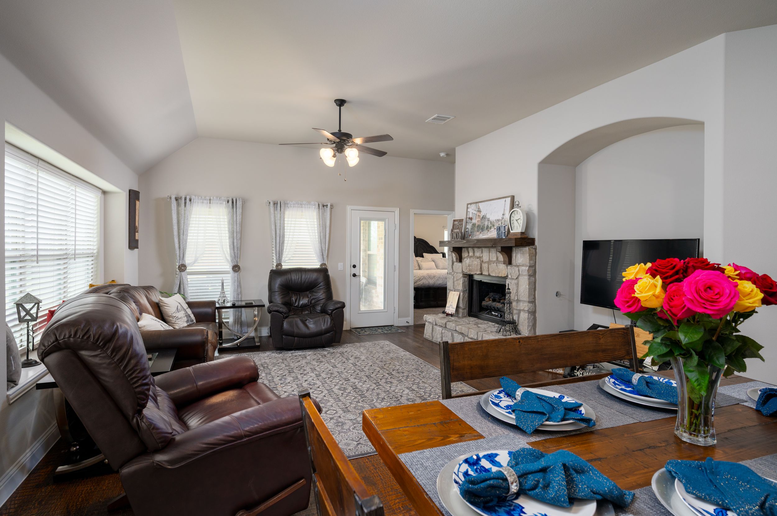 Contemporary living space with vaulted ceilings, ceiling fan, and entertainment center.