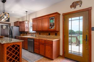 Panoramic view of a modern kitchen with cherry wood cabinets, granite countertops, and built-in wine rack storage.