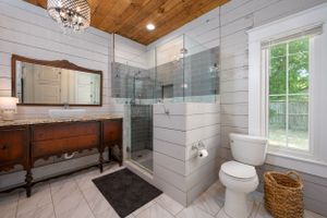 Modern farmhouse bathroom with shiplap walls, glass shower enclosure, and wood ceiling detail.