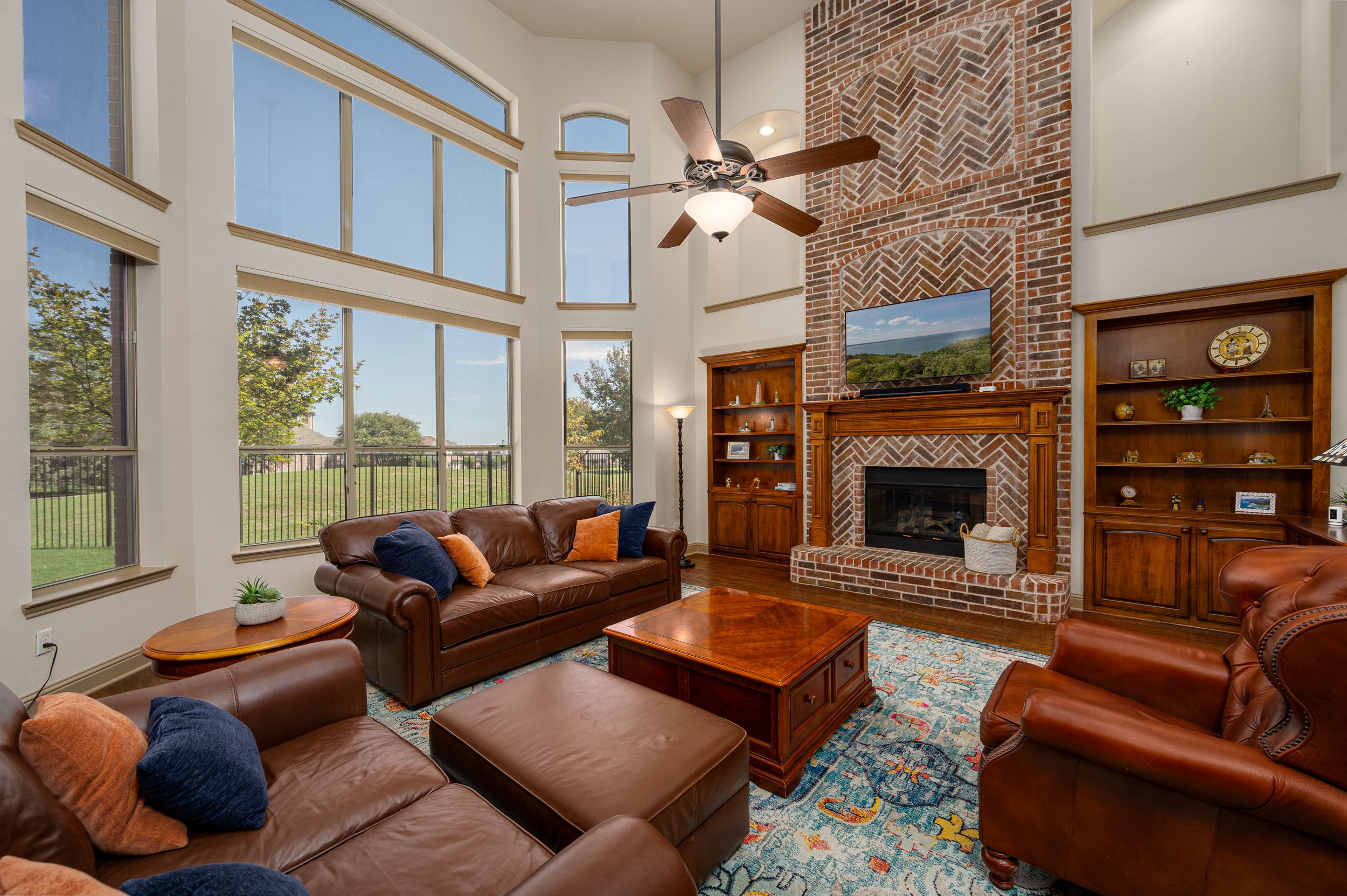 Elegant living room with exposed brick walls, large windows, and comfortable brown leather seating.
