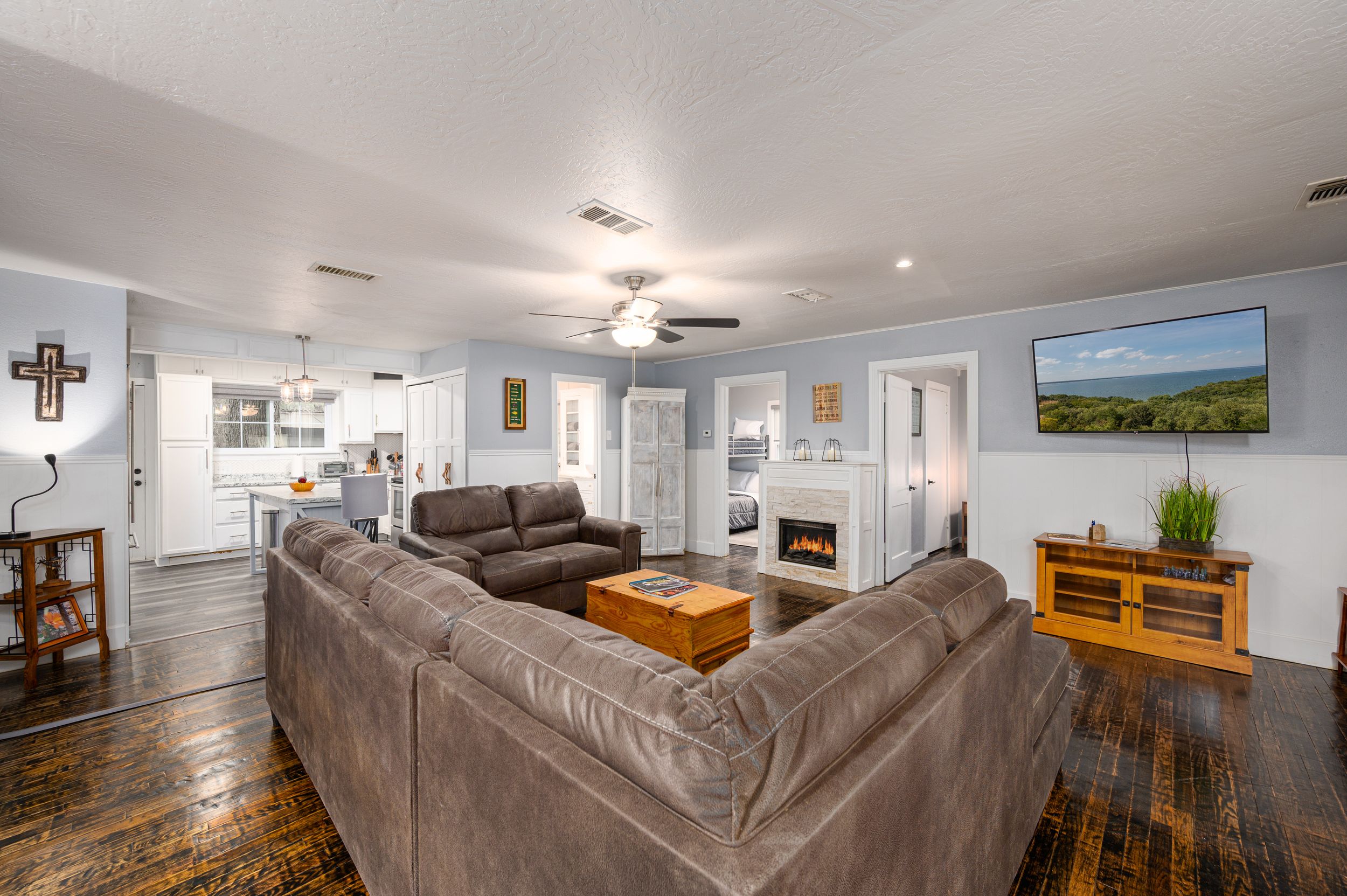 Spacious basement entertainment area with brown sectional sofa and hardwood flooring.