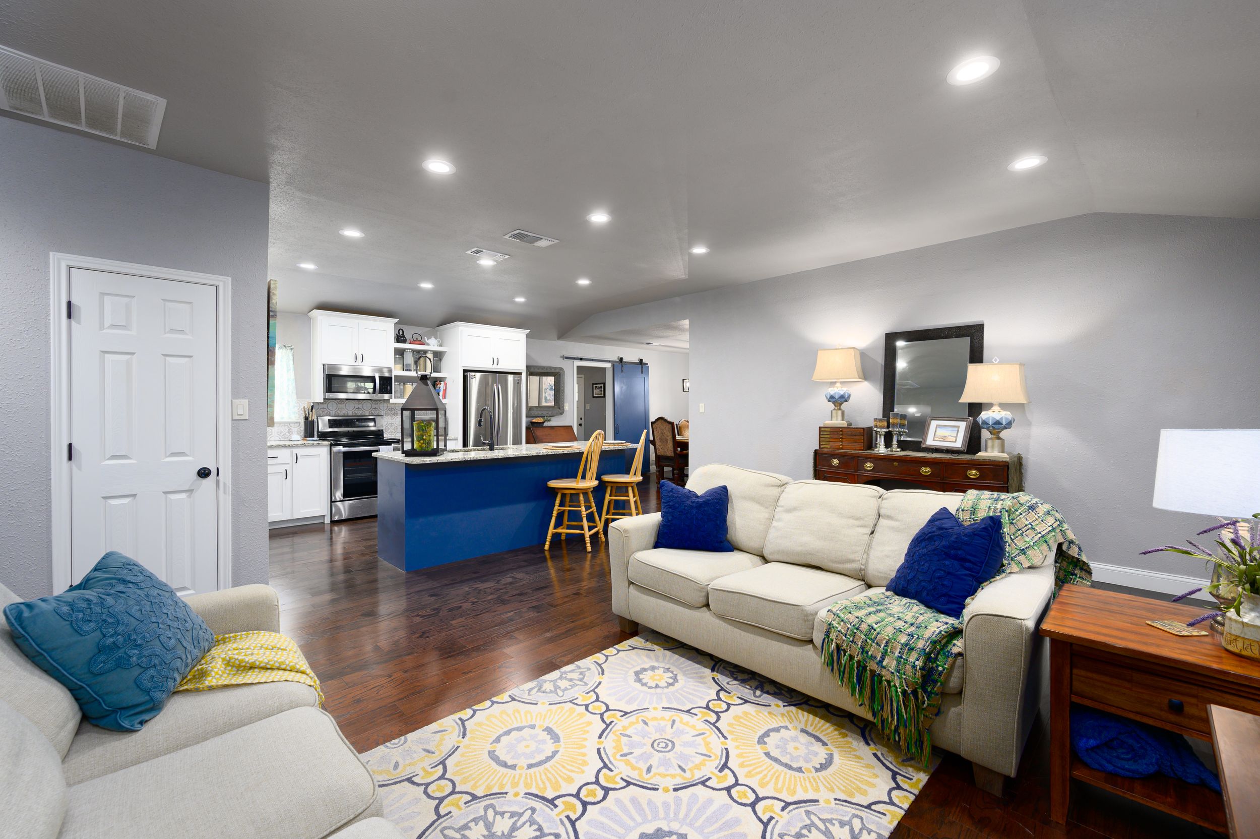 Modern basement living space with white walls, dark wood floors, and blue accent decor throughout multiple rooms.