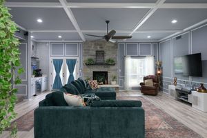 Modern living room features emerald green velvet sofa against white walls with LED ceiling lights and a textured area rug.