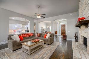 Spacious open concept living room with plush grey sofa, decorative pillows, and modern decor on marble floors.