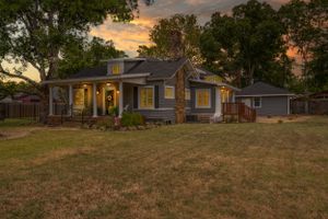 Panoramic sunset view of a charming suburban house with well-maintained lawn and mature trees.