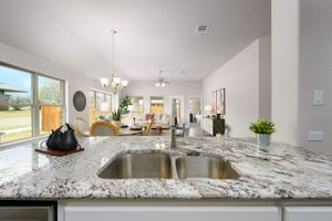 Contemporary kitchen with granite countertops, stainless steel appliances, and pendant lighting over island.