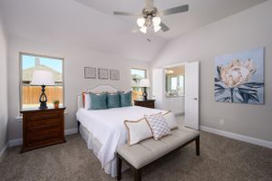Bright, airy bedroom with ceiling fan, grey walls, and large windows providing natural light.